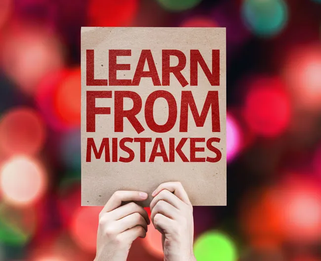 person holding up a card saying Learn From Mistakes